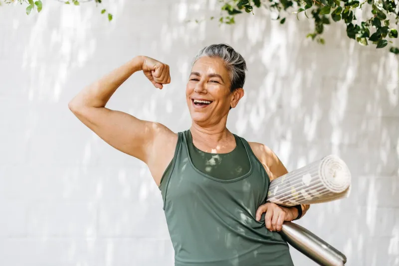 senior woman flaunting her strong bicep and looking at the camera, celebrating her fitness achievement after a workout session happy elderly woman taking pride in her fitness journey and the physical strength she has achieved