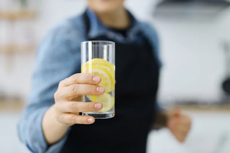 close-up, a glass of lemon water in a woman's hand