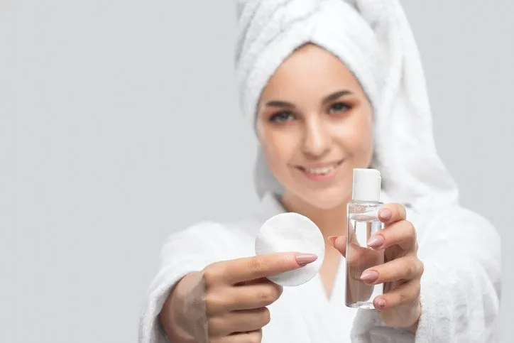 beautiful smiling woman with clean skin holds a cotton pad she cleanses the skin with a tonic cosmetology and professional skin care