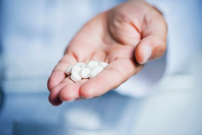 closeup of a caucasian doctor man, in a white coat, giving some pills to the observer