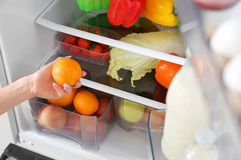 woman taking fruit from fridge
