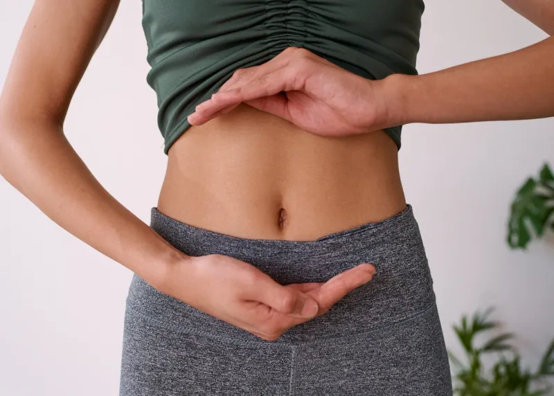 close up of a young multi-ethnic woman's stomach cupped by her hands high quality photo