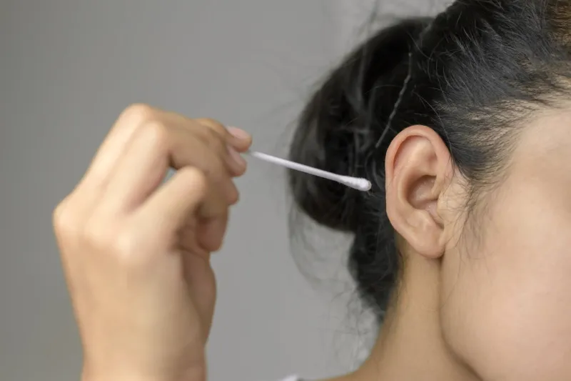 concept of cleaning in the ear hole woman cleaning ear with cotton bud