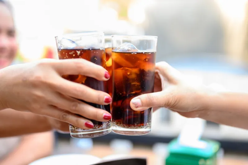 the woman's hand holds a glass of black soft drinks to drink