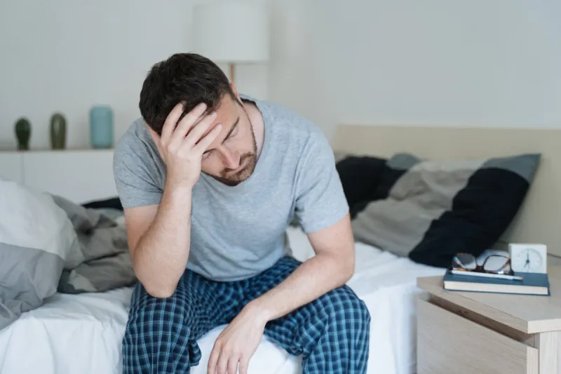 restless man waking up early with headache after rough night