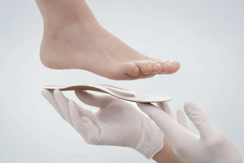 orthopedic insole isolated on a white background hands in rubber gloves hold an orthopedic insole foot care, comfort for the feet doctor orthopedist tests the medical device flat feet correction