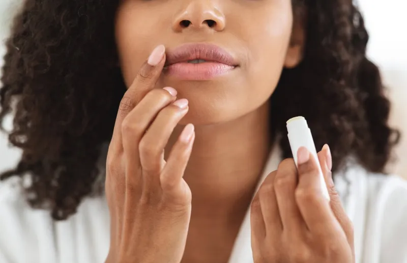 lip care unrecognizable black woman applying moisturising chapstick on lips, cropped image, closeup