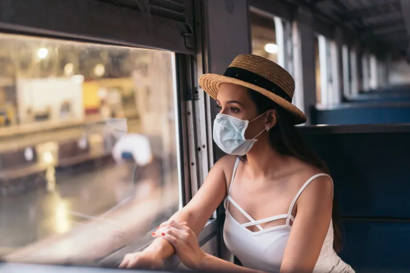 young brunette woman traveling in thailand on train during pandemic coronavirus 20s hispanic in a protective mask wear summer sleeveless clothes and backpack in asia