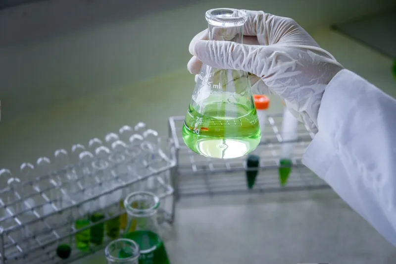 the scientist is testing the natural product extraction and green color solution, in the chemistry laboratory