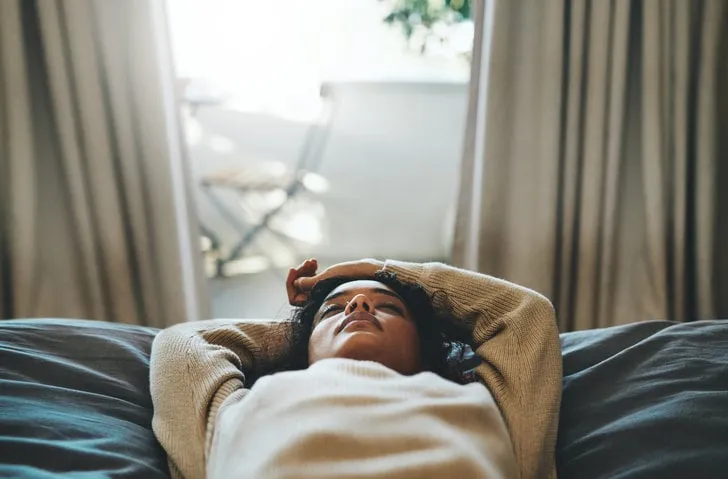 cropped shot of a young woman lying on her bed with her eyes closed