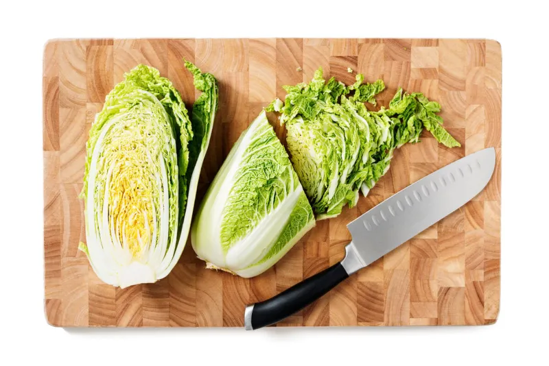 cutting board with fresh cut chinese cabbage isolated on white background top view