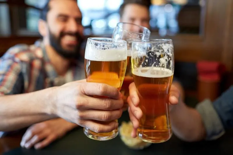 gens, hommes, loisirs, amitié et célébration concept - heureux amis masculins, boire de la bière et tinter les verres au bar ou au pub