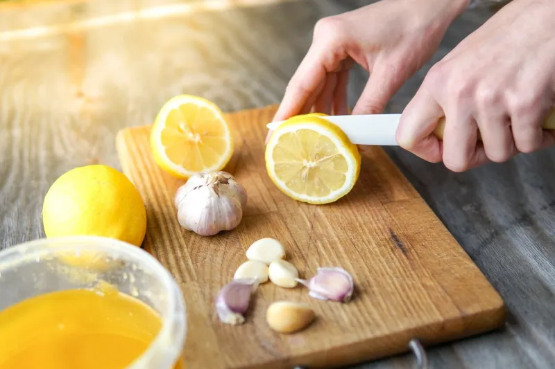 alternative medicine with lemon, garlic and honey over rustic background woman prepare healthy treatment