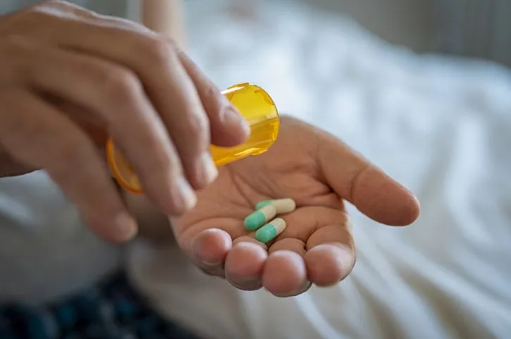 closeup of man hand pouring capsules from a pill bottle into hand senior man taking daily medicine to consume close up of male hands taking daily dose of drug