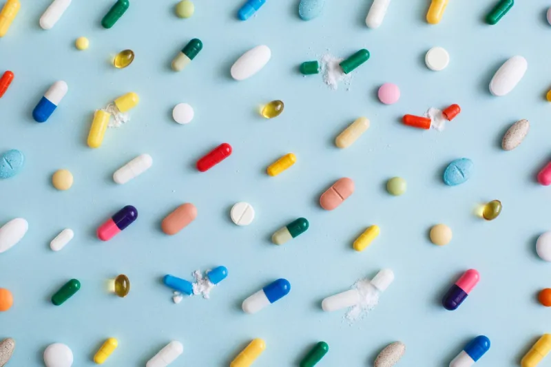 creative layout of colorful pills and capsules on blue background minimal medical concept pharmaceutical, covid-19 or coronavirus flat lay, top view