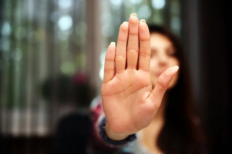 woman with her hand extended signaling to stop (only her hand is in focus)