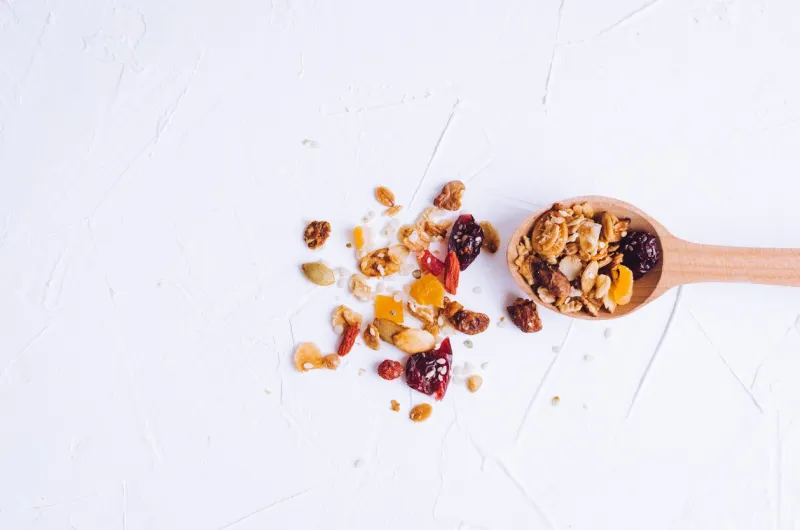 delicious homemade granola on wooden spoon on white background breakfast healthy food sweet dessert snack diet nutrition concept vegetarian food flat lay top view copy space