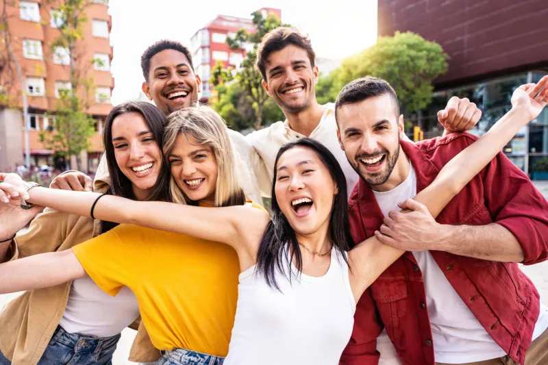multiracial best friends having fun outside - group of young people smiling at camera outdoors - friendship concept with guys and girls hanging out on city street