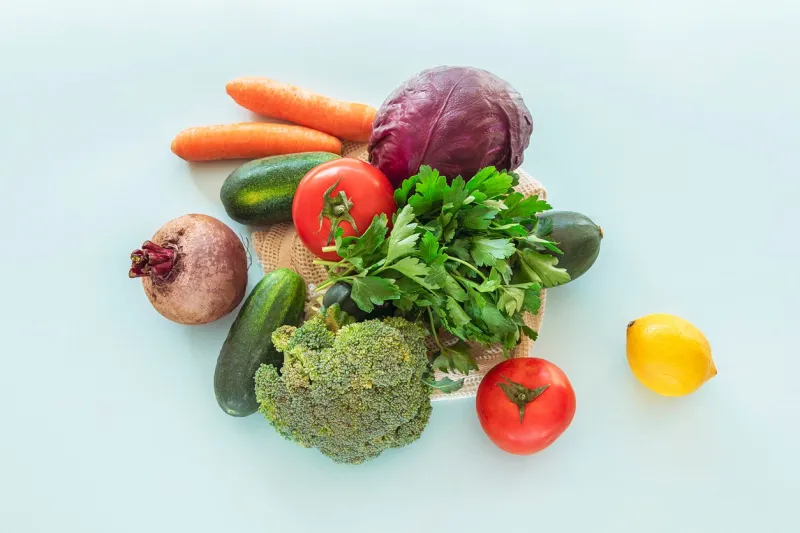 assortment of colorful vegetables in reusable bag, zero waste concept top view, flat lay blue background