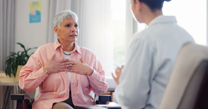 doctor, consultation and elderly woman with chest pain for heart disease, advice and medical checkup healthcare, patient and worker with discussion for cardiac arrhythmia, palpitations and diagnosis