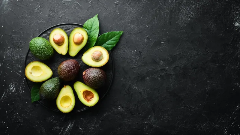fresh avocado with leaves on a black background top view free space for your text