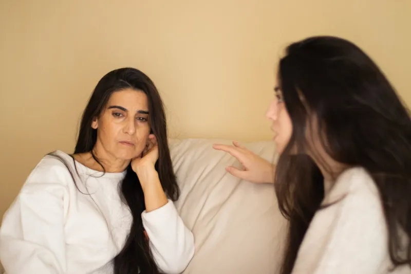 mother and daughter discussing sitting on a sofa