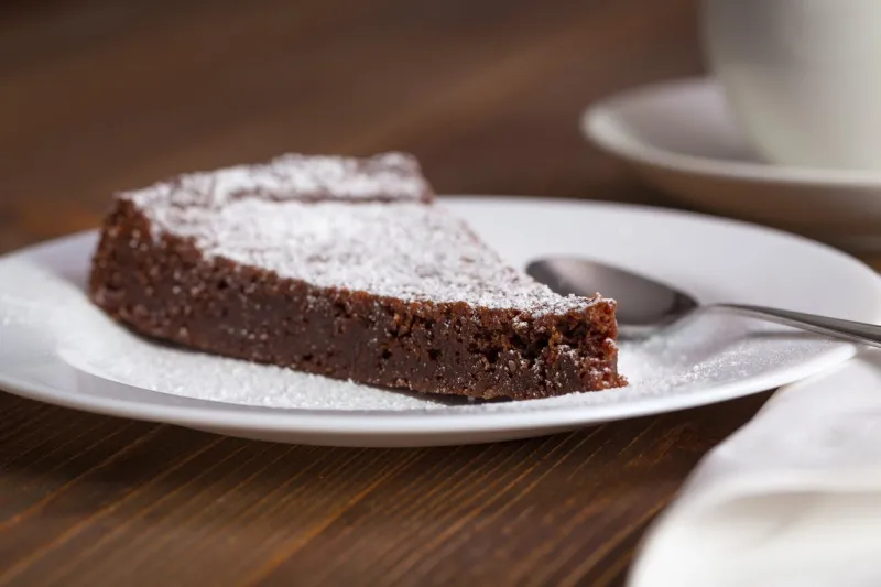 chocolate cake slice on white dish and wooden background
