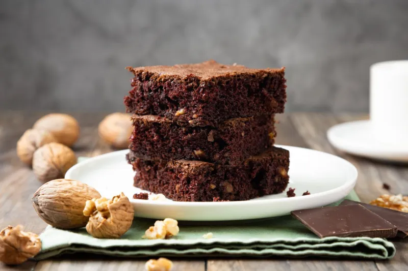 chocolate brownie cakes with walnuts on a stack on a rustic wooden table