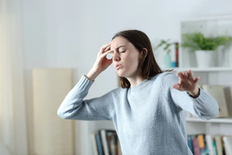 dizzy woman suffering vertigo attack standing in the living room at home