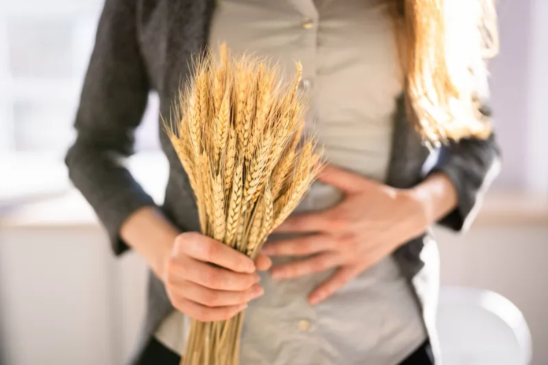 celiac disease and gluten intolerance women holding spikelet of wheat