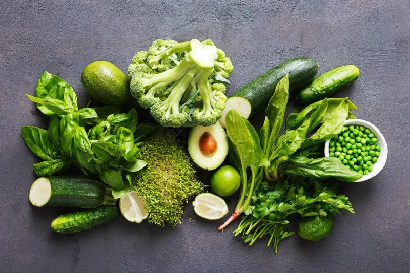 set raw healthy food clean eating vegetables source of protein for vegetarians  cucumber, lucerne, zucchini, spinach, basil, green peas, avocado, broccoli, lime on black background, top view