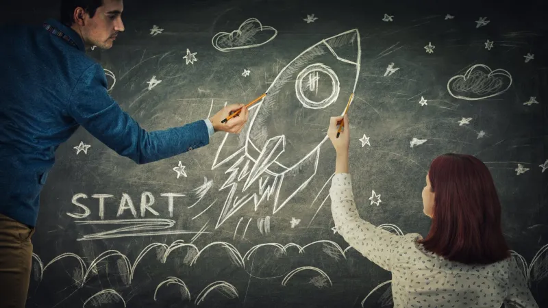 man and woman sharing thoughts together drawing rocket start on blackboard idea exchange, business launch and development partnership and teamwork innovation concept as ship take off in cosmos