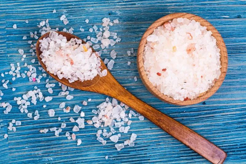 large pink sea salt on blue background studio photo