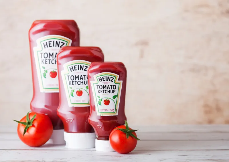 london, uk - march 10, 2018   plastic bottles of heinz ketchup on wooden background with raw tomatoes manufactured by hj heinz company