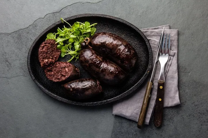 bloody sausages on cast iron plate top view