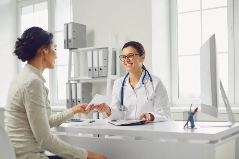 smiling female patient at consultation with woman doctor sitting at table in office clinic medicine clinic hospital