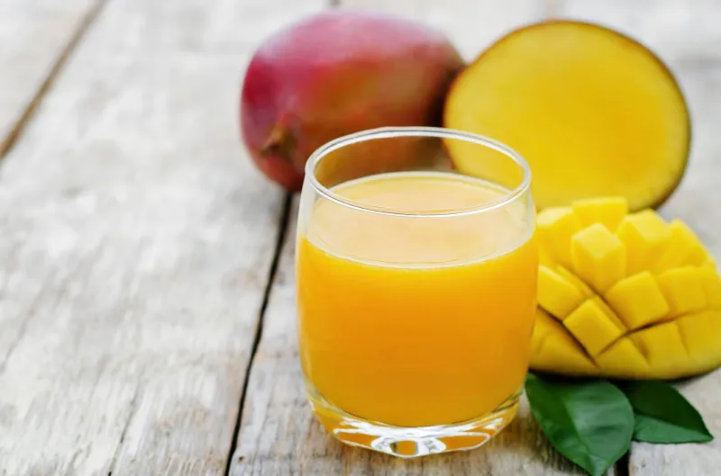 jus de mangue et mangue fraîche sur un fond de bois blanc teintant mise au point sélective