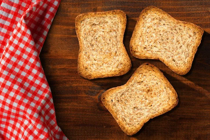 three healthy rusks of wholemeal flour on a wooden table with red and white checkered tablecloth