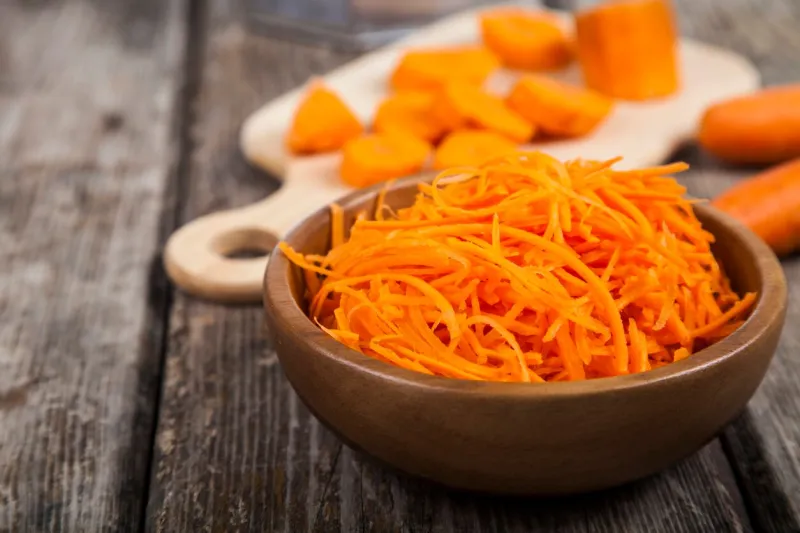 grate carrots in a bowl on a wooden table tasty and healthy food diet