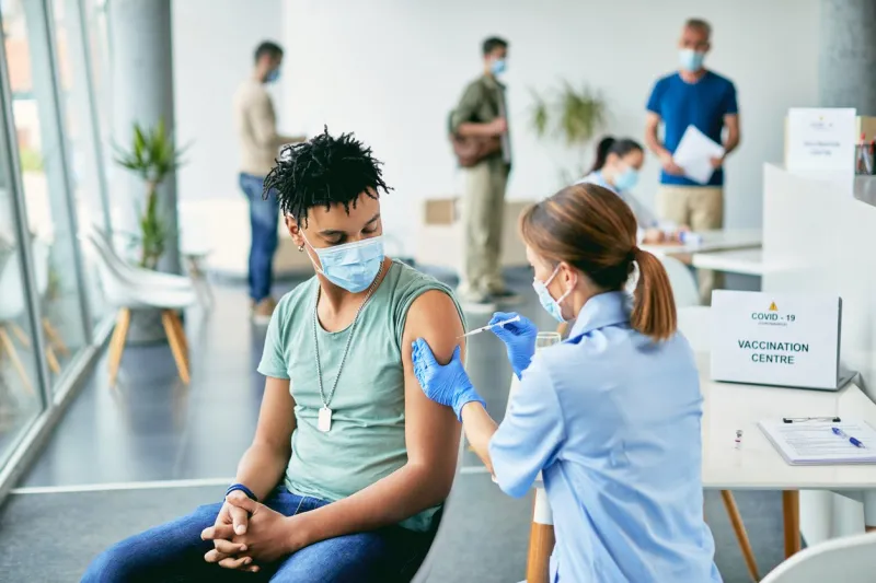 young african american man getting vaccinated against coronavirus at vaccination center