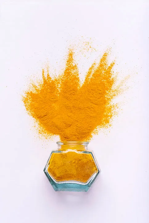 from the glass bowl a sprinkling of turmeric on a white background seen from above