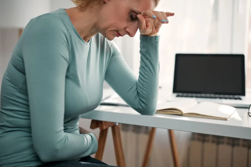 woman with stomach spasm, cramp, headache, head pain, working from home troubles and issues