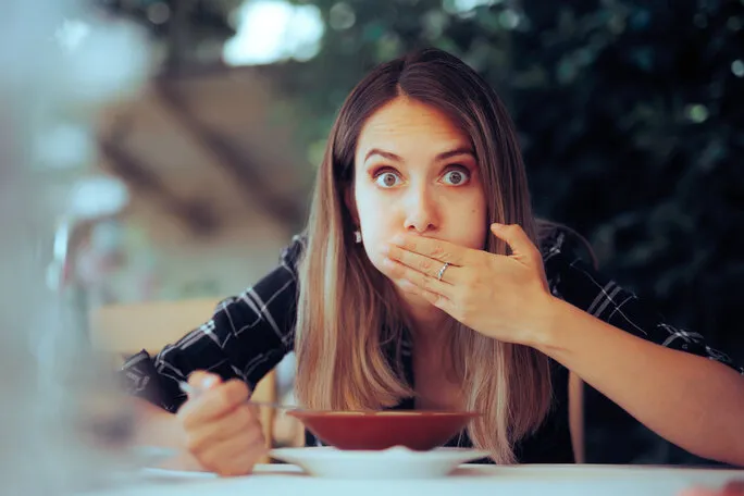 woman trying food feeling sick instantly from first chewing restaurant customer feeling nauseated and displeased with the serving