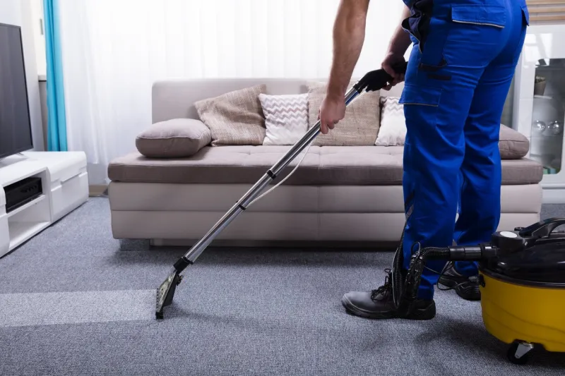 janitor's hand cleaning carpet with vacuum cleaner
