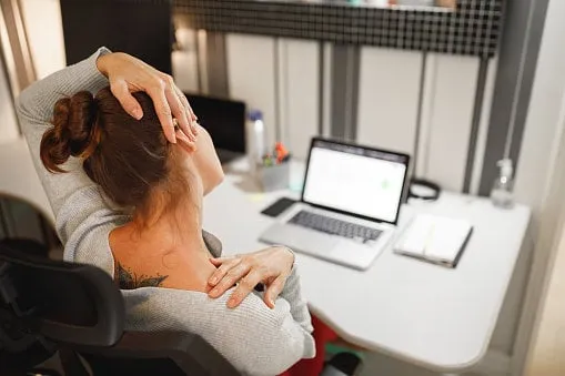 woman stretching her neck while working at home
