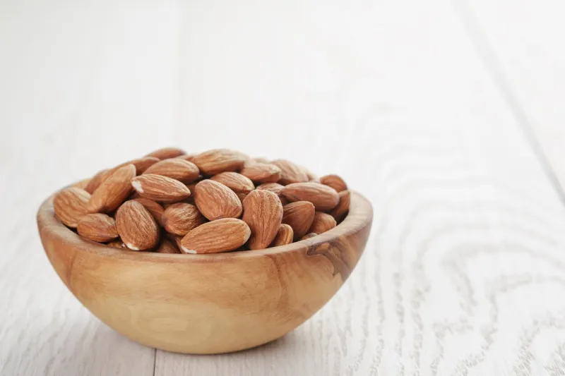 roasted almonds in bowl on white wooden table, shallow focus