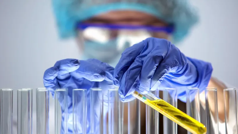 female chemist holding test tube with litmus paper inside, laboratory experiment