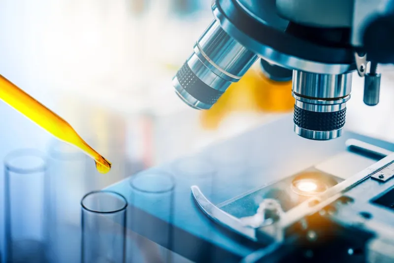 dropping yellow liquid sample to test tube with microscope medical, pharmaceutical and scientific research and development concept
