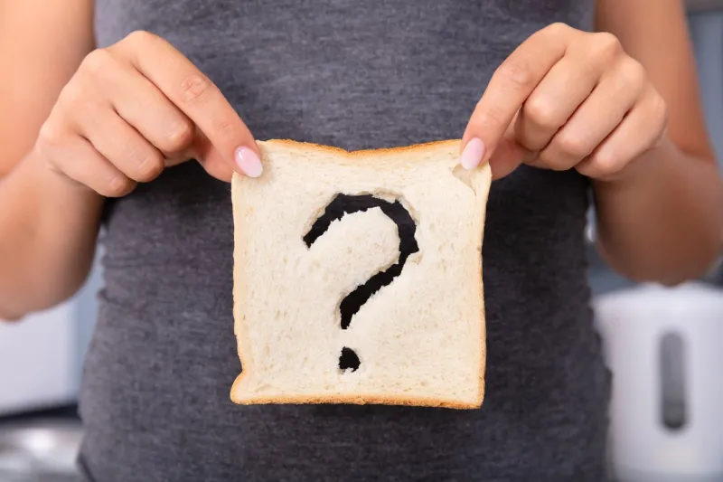 mid-section of a woman hands holding sliced bread with question mark sign