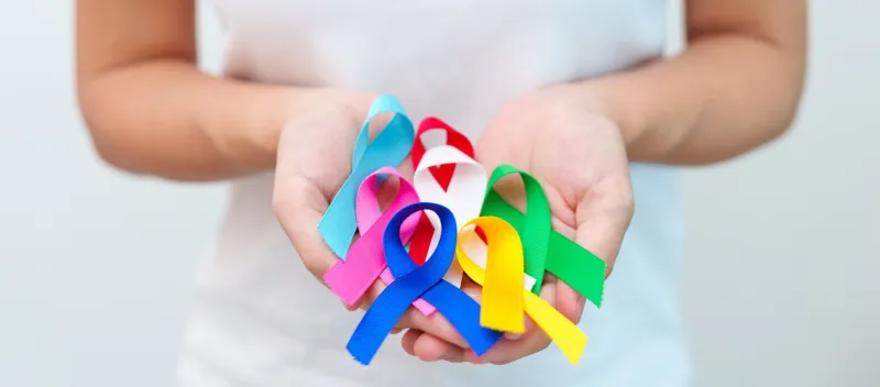 world cancer day, february 4 hand holding blue, red, green, white, pink, navy blue and yellow ribbons for supporting people living and illness healthcare and autism awareness day concept